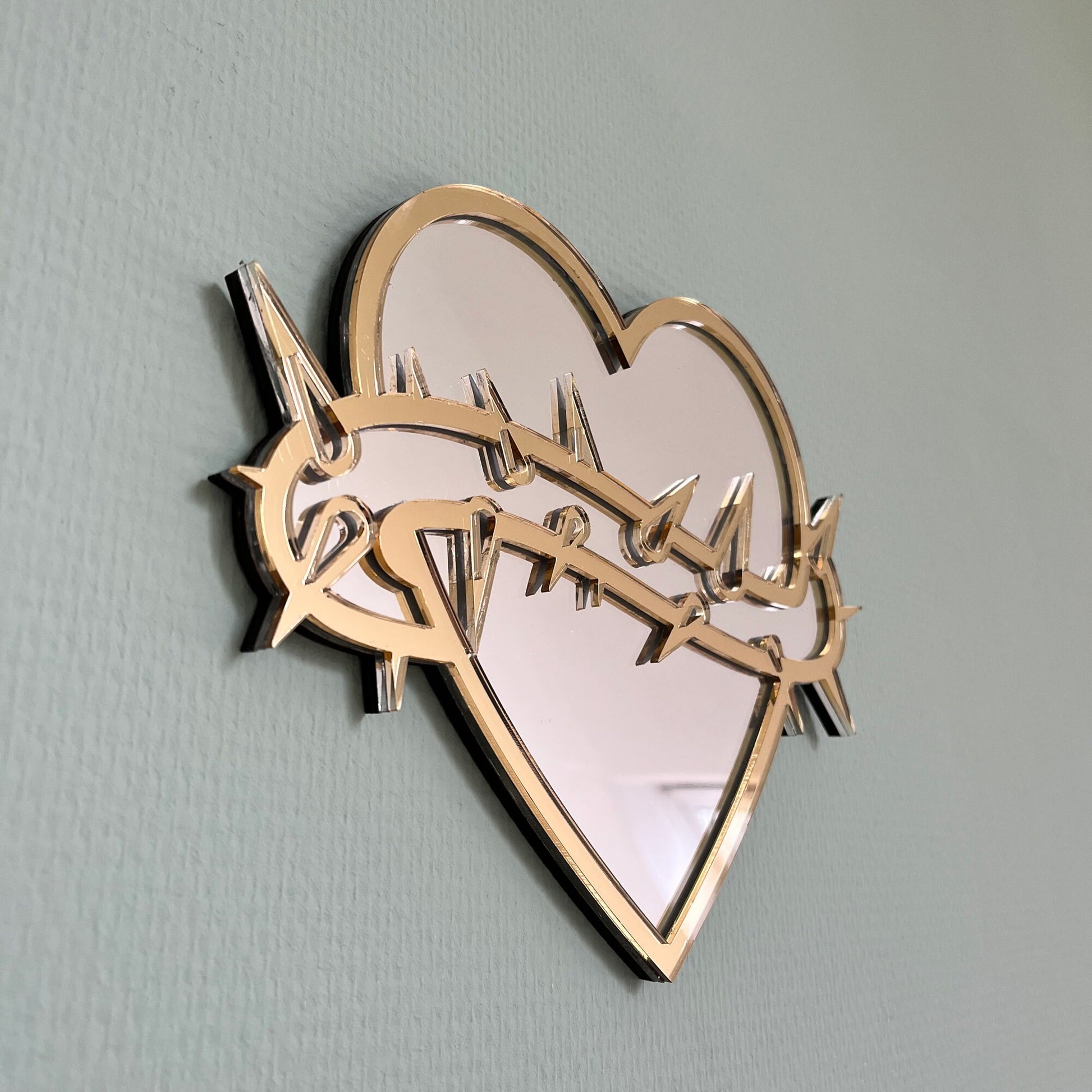 Lekky Studio's Exclusive Heart Mirror: Unique thorn design in traditional tattoo style, with luxurious gold and silver accents. Size: 29x22cm. Hand-assembled, laser-cut acrylic for a bespoke artistic touch to your decor.