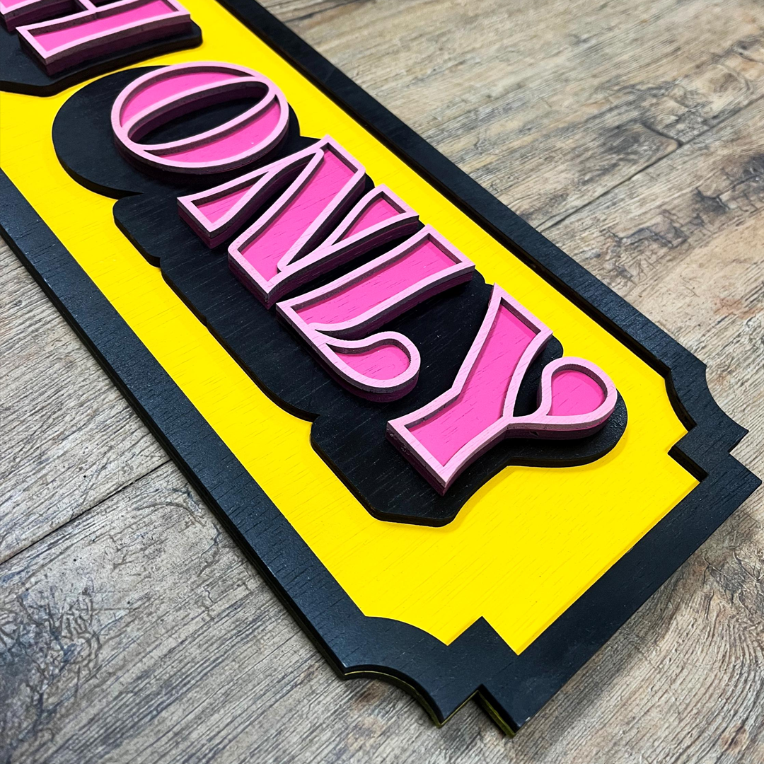 "Cash Only" bord van gelaagd hout met een retro design in roze, geel en zwart in tattoo shop.