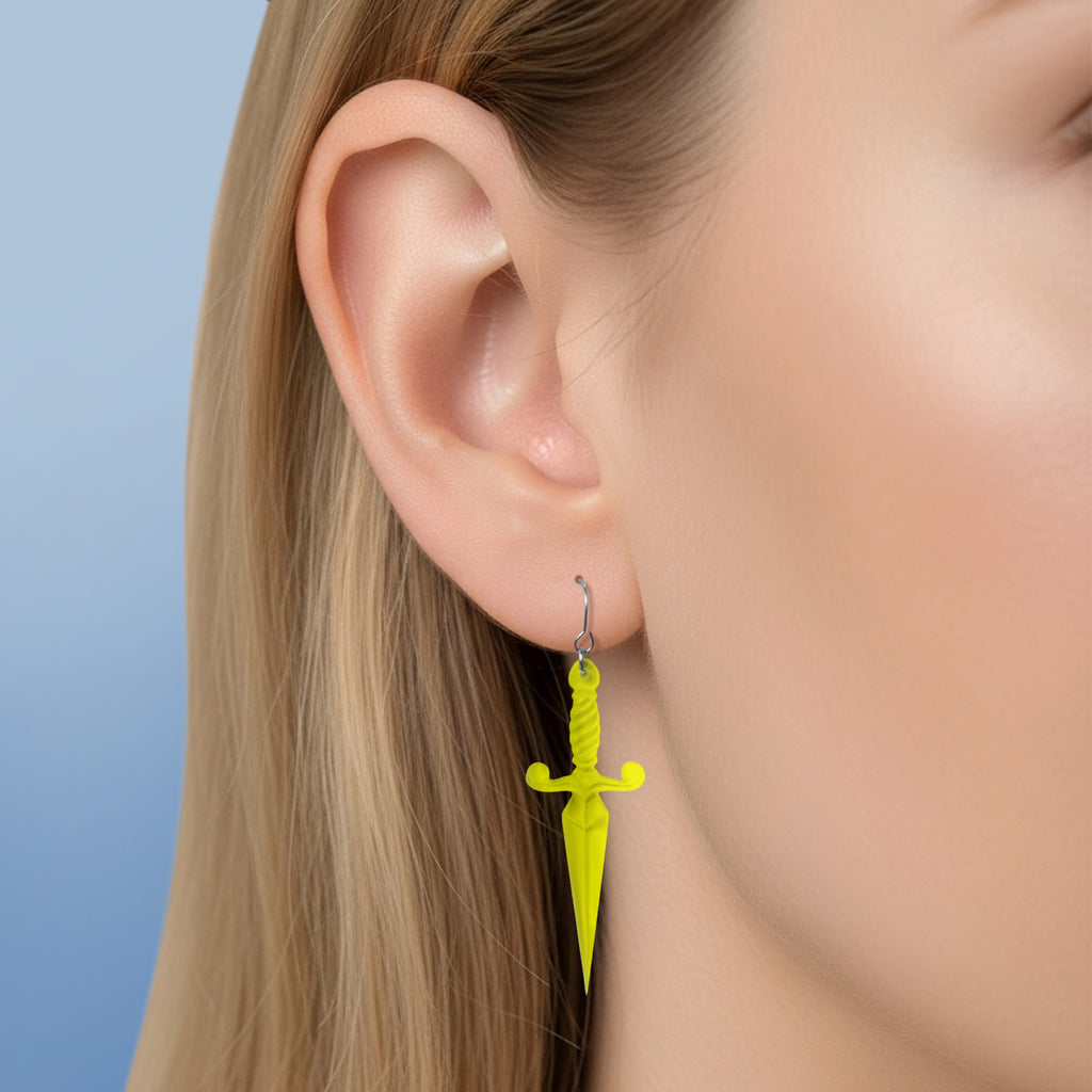 Tattooed woman with handgemaakte gele acryl dolk oorbellen in traditionele tattoo flash stijl, gemaakt in Nederland.