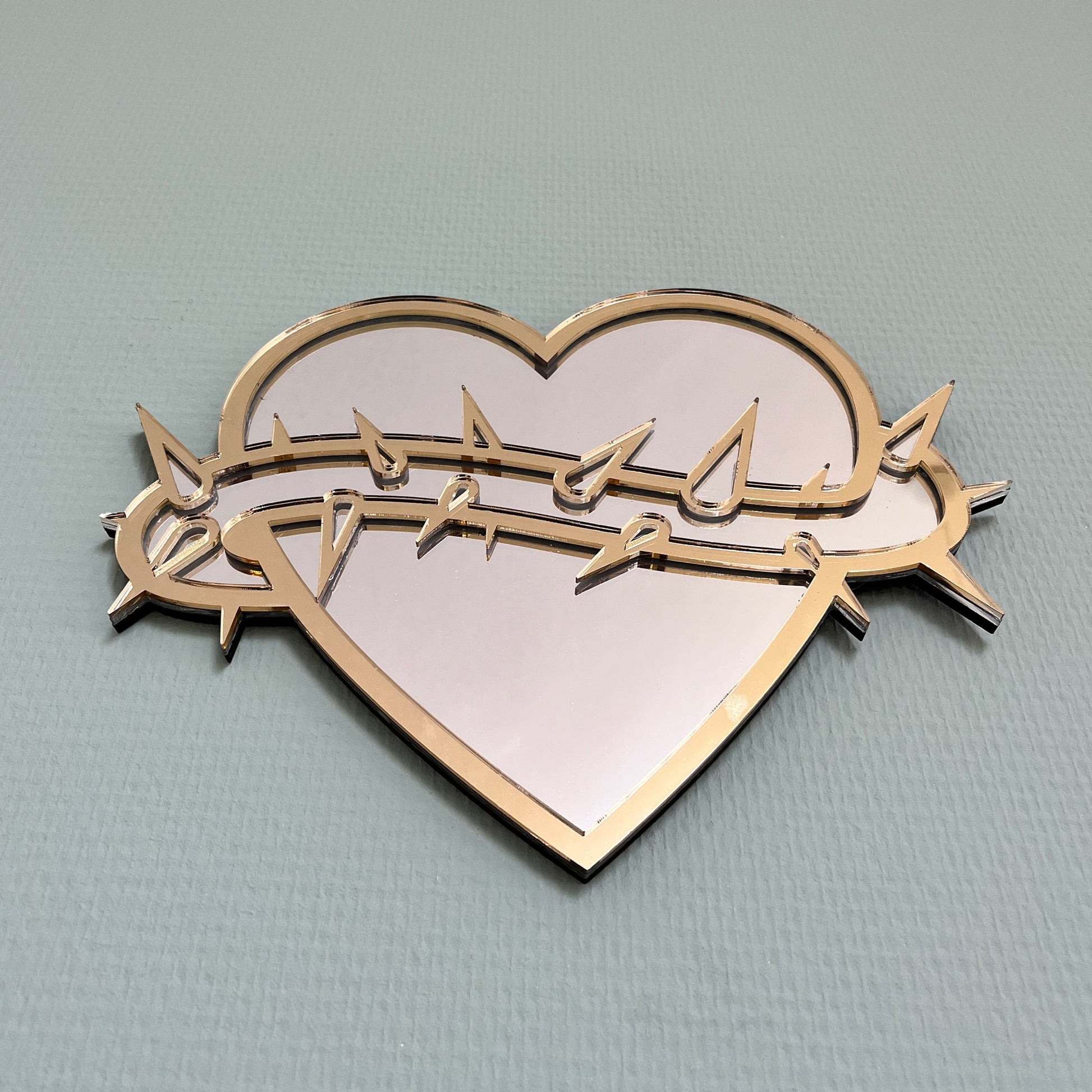 Lekky Studio&#39;s Exclusive Heart Mirror: Unique thorn design in traditional tattoo style, with luxurious gold and silver accents. Size: 29x22cm. Hand-assembled, laser-cut acrylic for a bespoke artistic touch to your decor.